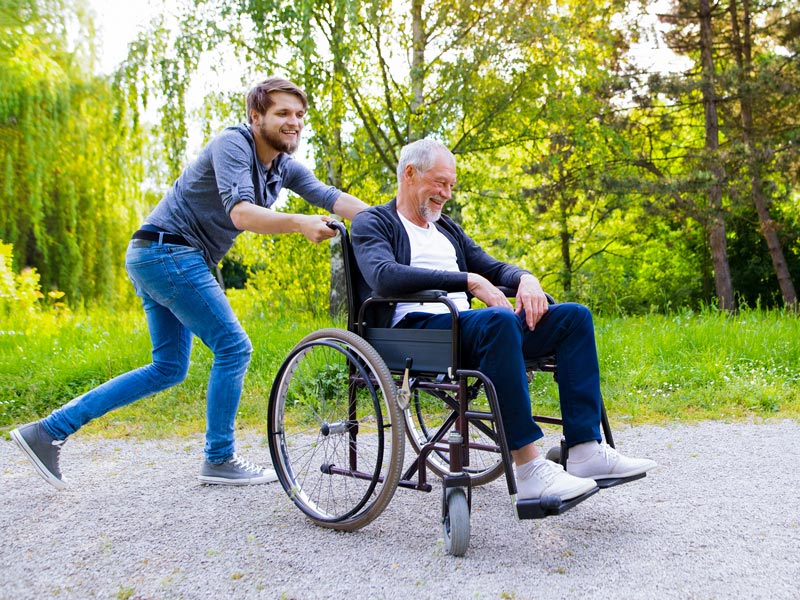 man pushing senior in wheelchair